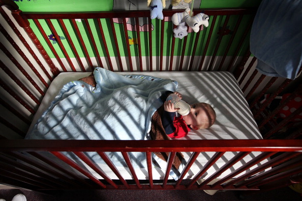 DECATUR, IL - FEBRUARY 18:  Eight-month-old Skyler drinks a bottle in his crib in the room he shares with his mother Katrisa Parks at the Decatur Correctional Center February 18, 2011 in Decatur, Illinois. Skyler, who was born while Parks was serving a ten-year sentence for burglary, lives with his mother at the prison, part of the Moms with Babies program at the minimum security facility. The program allows incarcerated women to keep their newborn babies with them for up to two years while serving their sentence. The program boasts a zero percent recidivism rate compared to the statewide rate of 51.3 percent.  (Photo by Scott Olson/Getty Images)