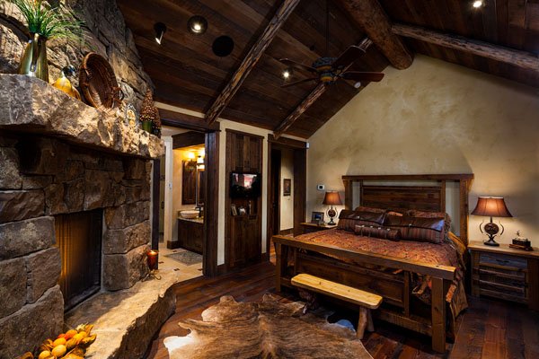 rustic-fireplace-in-bedroom-with-wooden-bed-wooden-floor-exposed-wooden-beams-ceiling-wooden-bedside-table-with-beautiful-bedside-table-lamps-on-it