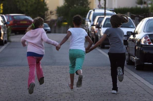 Three Girls Running Through The Street Holding Hands