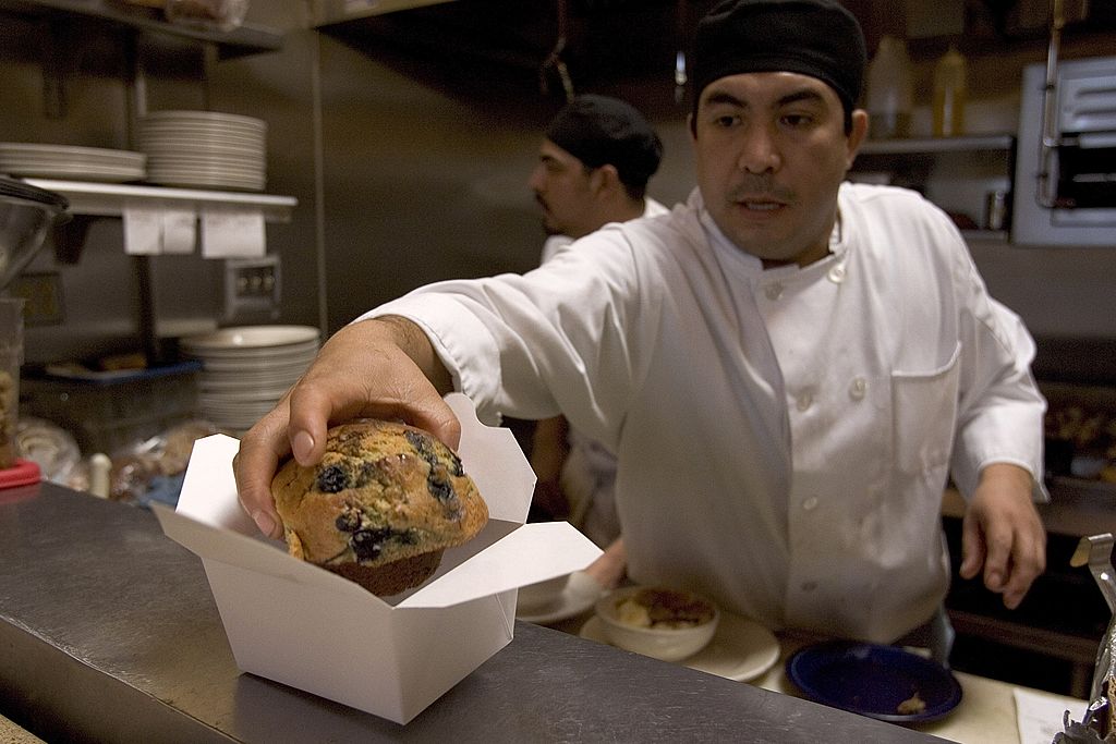 Chef Alfredo Mora puts a blueberry muffin in a paper take out container