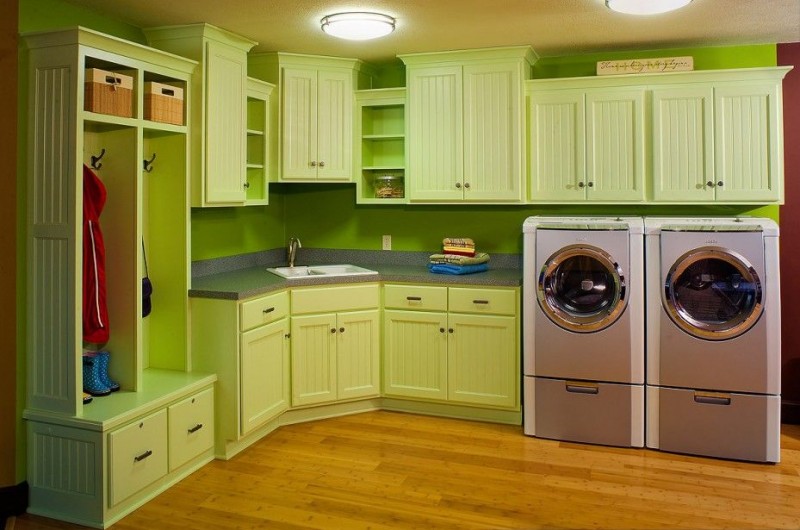 Laundry room with bright green cabinets and wooden floors