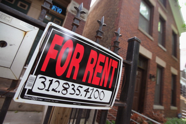 "For Rent" sign stands in front of a house 