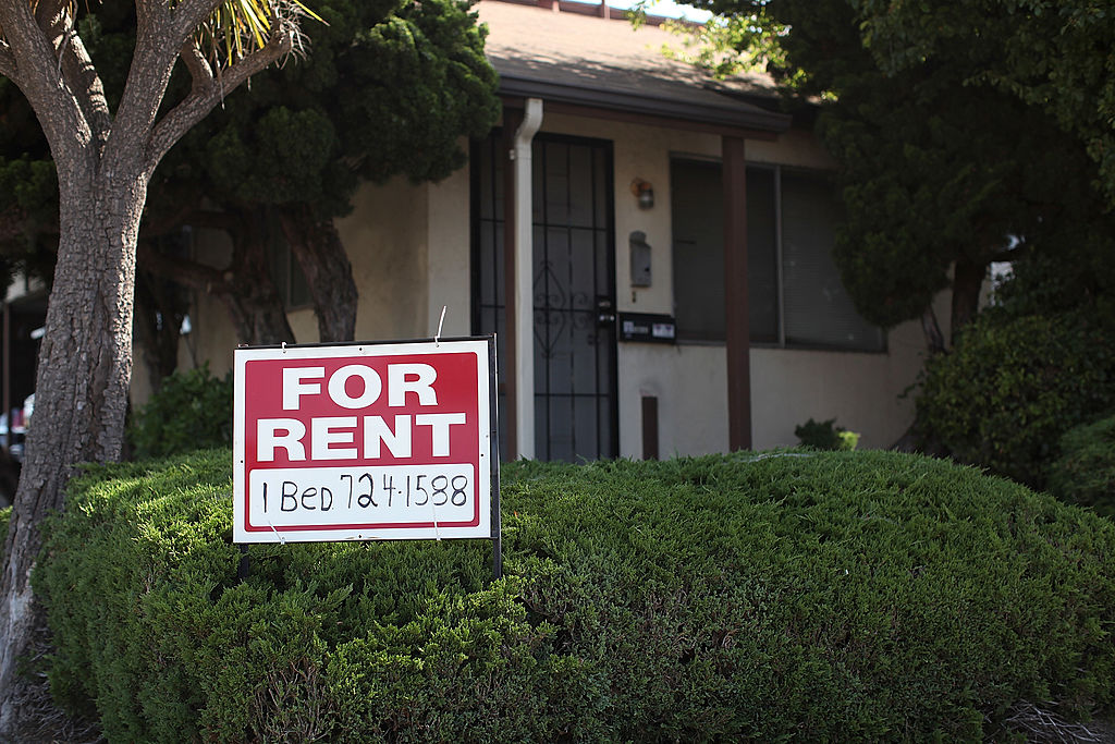 A "for rent" sign is posted in front of a house