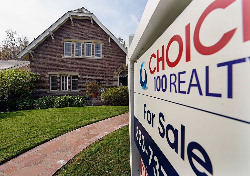 A "For Sale" sign is posted in front of a house