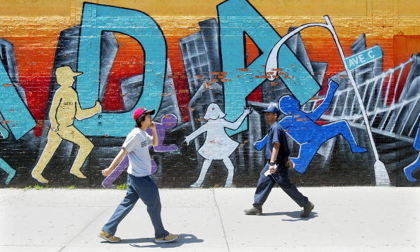  Men walk past a mural on Avenue C 