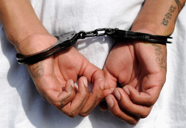 Handcuffs are seen on the hands of a twenty-year old "Street Villains" gang 