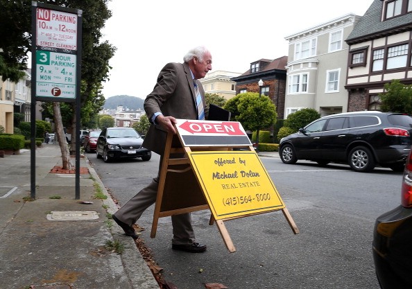 Real estate agent Maurice Dolan places an open house sign in front of a home for sale