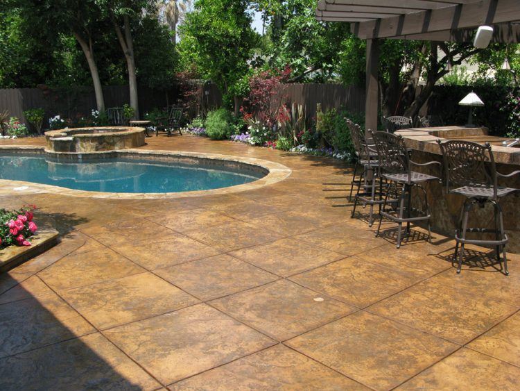 concrete patio surrounded by pool