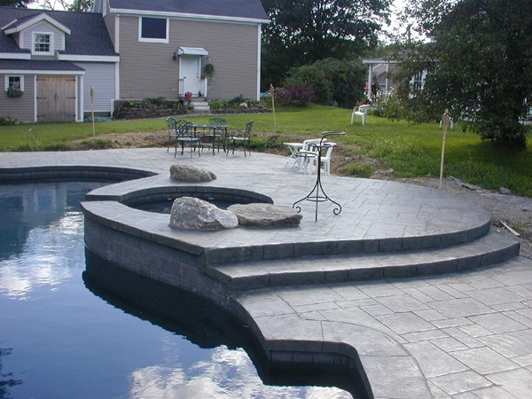 concrete patio near backyard swimming pool