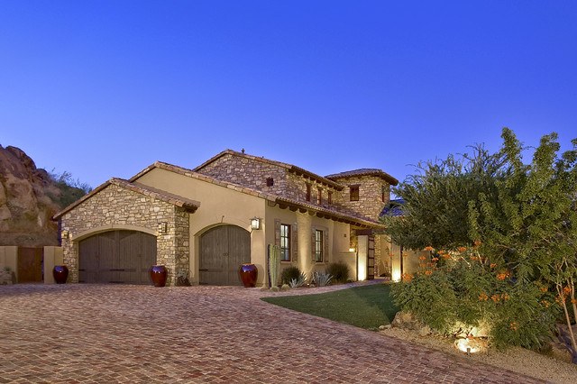 mediterranean home with brick driveway