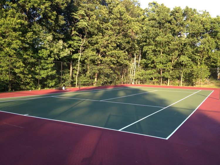 simple home tennis court surrounded by trees