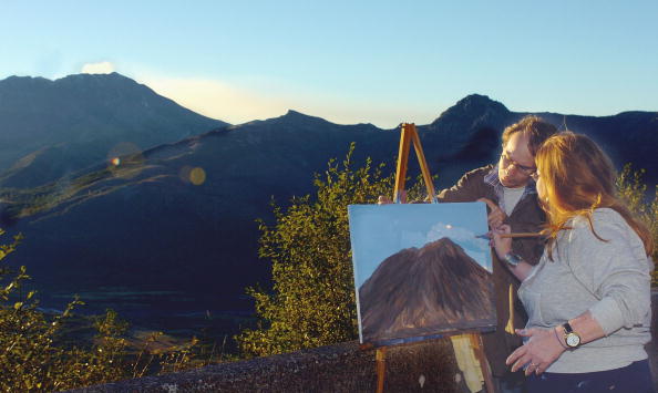 Teri Dewey, right, from Olympia, Washington, assisted by her husband, Joe Dewey, paints a steam plume onto her painting of Mount St.Helens, after setting up her easel to catch the sunrise at Elk Creek Overlook on  October 14, 2004 near Mount St. Helens, Washington. 