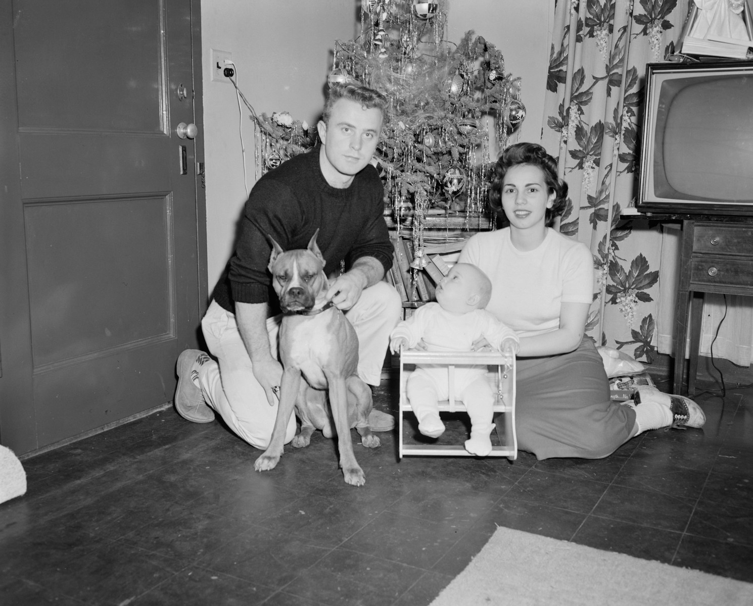 grayscale photo of boy sitting beside dog on floor