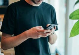 man in black crew-neck top using smartphone