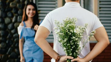 Man Holding Baby's-breath Flower in Front of Woman Standing Near Marble Wall