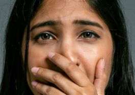 Close-up Portrait of Terrified Woman Covering Mouth with Hand