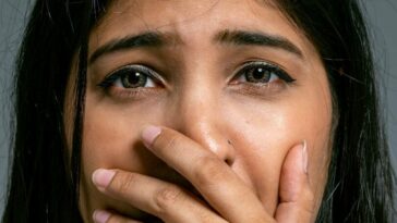 Close-up Portrait of Terrified Woman Covering Mouth with Hand