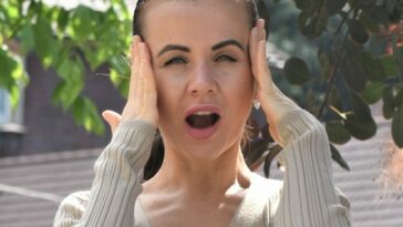 a woman holding her hands up to her ears