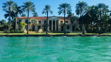 brown and white concrete house near body of water ahead