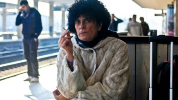 man sitting and smoking at the train station