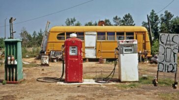 an old gas station with a yellow bus in the background