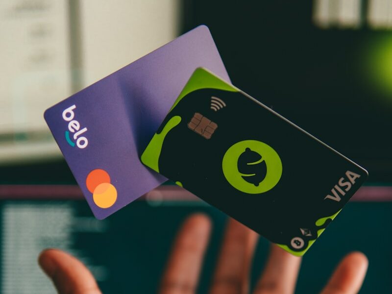 a hand holding a credit card in front of a computer