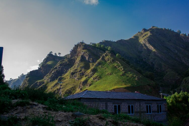 brown and gray house on green mountain under blue sky during daytime