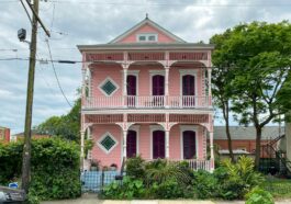 a pink and white house with a car parked in front of it