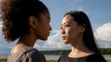 A close-up outdoor portrait of two women facing each other under a bright sky.
