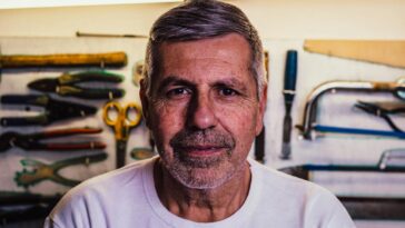 Portrait of a senior man with tools in the background, exuding confidence.
