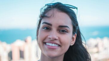 Portrait of a happy woman smiling with sunglasses on head, city skyline view.