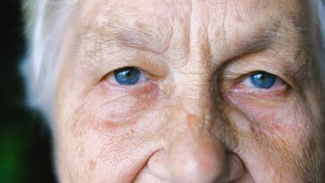Detailed close-up of an elderly woman's face showcasing her blue eyes and age-lines.