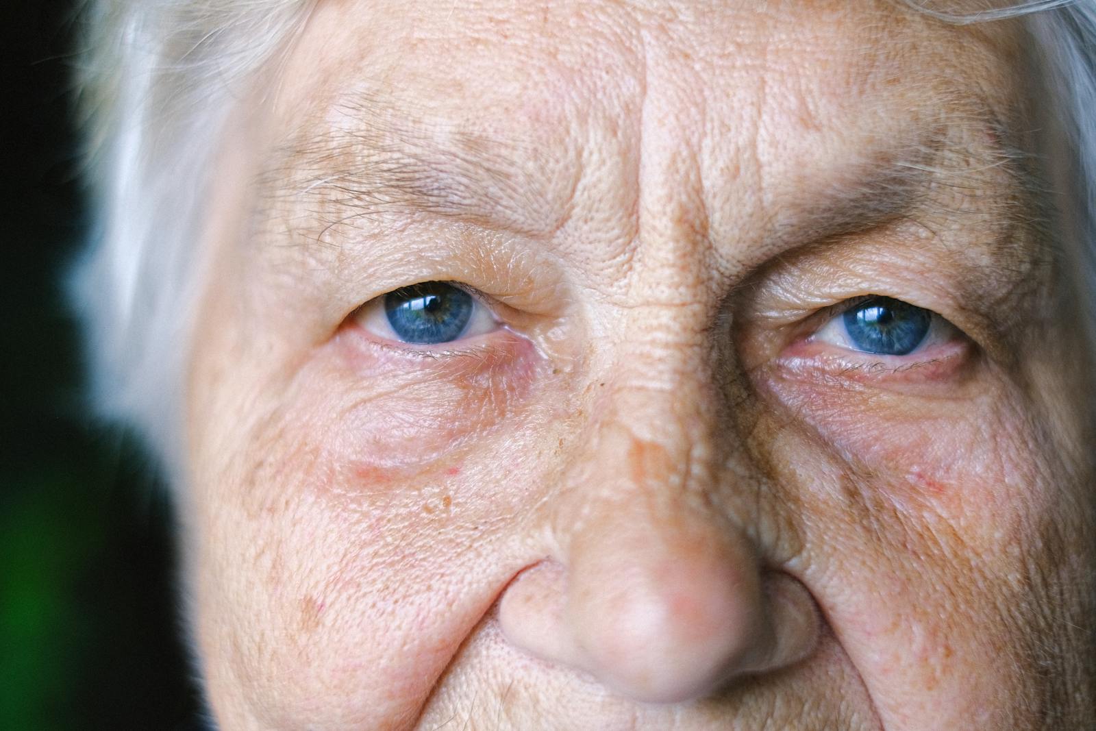 Detailed close-up of an elderly woman's face showcasing her blue eyes and age-lines.
