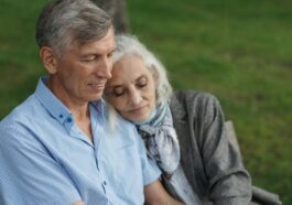 An elderly couple sitting on a bench in a park, sharing a tender moment of love and companionship.