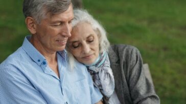 An elderly couple sitting on a bench in a park, sharing a tender moment of love and companionship.