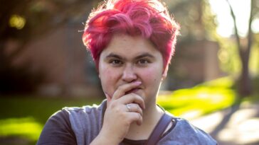 a woman with pink hair and a ring on her finger