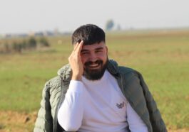 a man with a beard sitting in a field