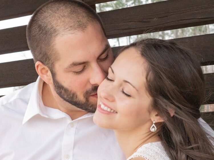 man in white dress shirt kissing woman in white sleeveless dress