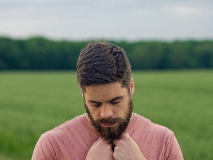 man in pink long sleeve shirt standing on green grass field during daytime