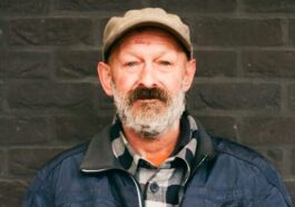 man in blue zip up jacket and brown hat