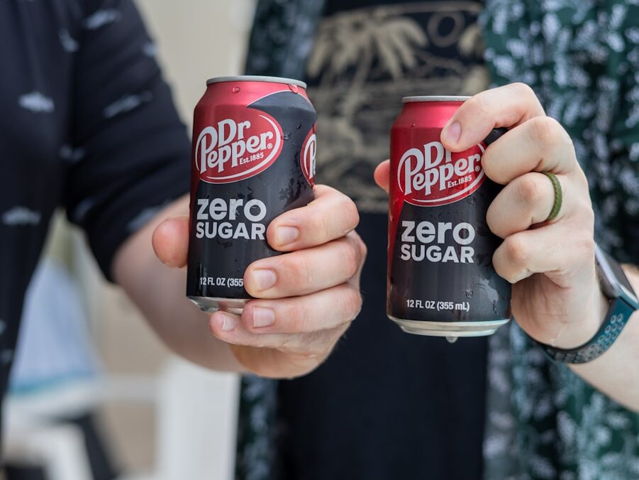 Two people are holding cans of dr. pepper zero sugar.