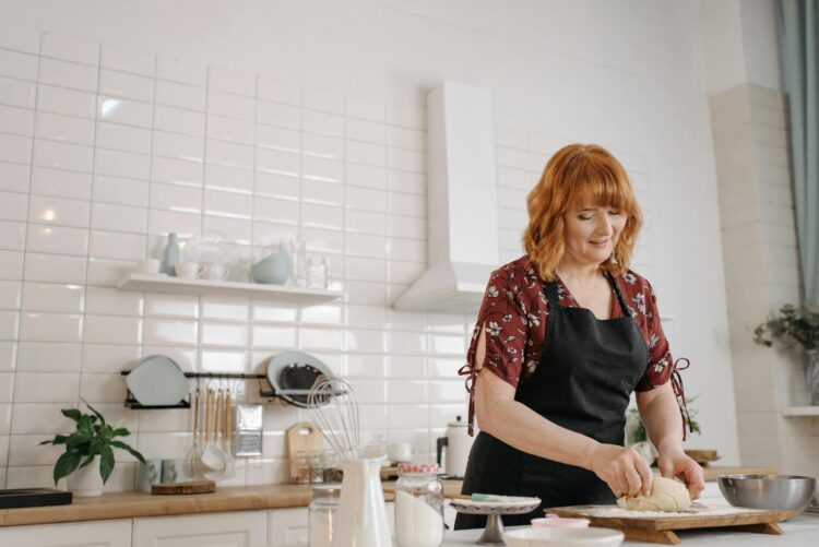 Adult woman in a kitchen preparing dough for baking. Simple and cozy kitchen ambiance.