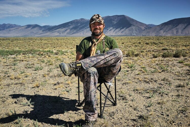 man sitting on folding camping chair in the middle of desert
