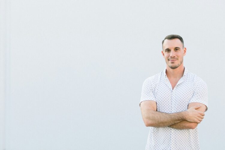 a man standing with his arms crossed in front of a white wall