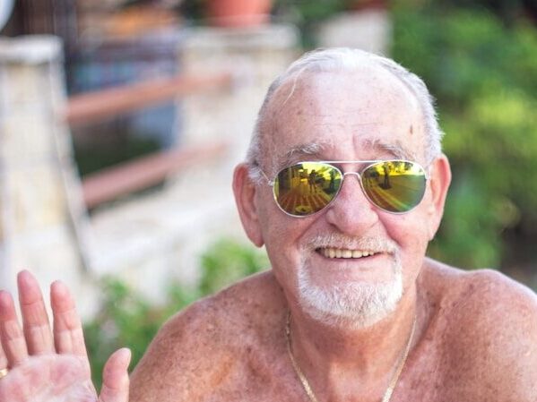 topless man wearing sunglasses sitting on chair