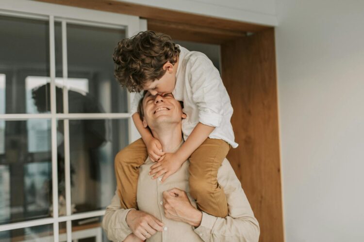 A joyful moment of a father carrying his son on his shoulders indoors.