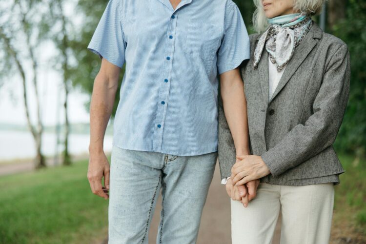 A senior couple enjoys a peaceful walk, holding hands in a serene park setting.
