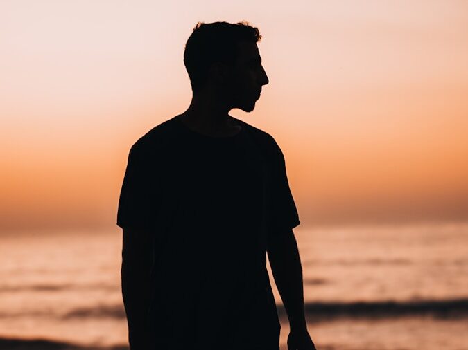 a man standing on top of a beach next to the ocean