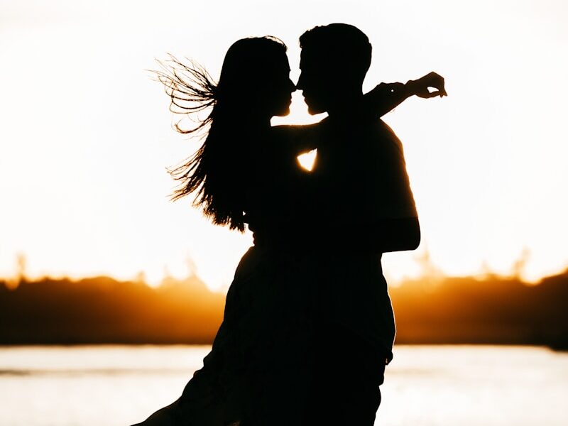silhouette of woman standing on beach during sunset