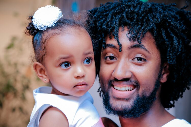 man in white top holding girl baby